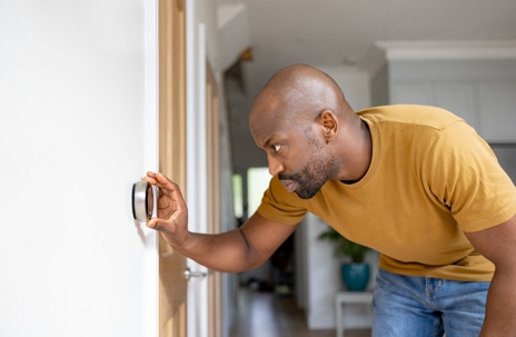 Man adjusting the temperature on the thermostat of his house.